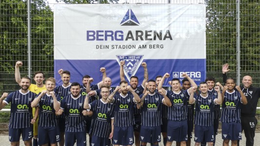 Aufsteiger in die Kreisliga A: Die 1. Fußball-Herrenmannschaft des TuS Hoberge-Uerentrup mit Trainer Ernad Selimovic präsentiert das neue Banner in der BERG-Arena.